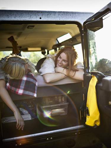 Zwei Frauen liegen auf der Rückbank ihres SUV.