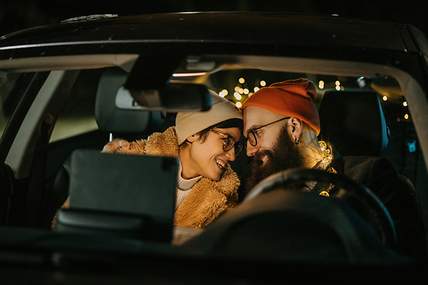 Zwei lachende Frauen sitzen in einem Auto. 