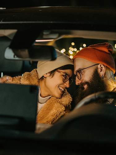 Zwei lachende Frauen sitzen in einem Auto. 