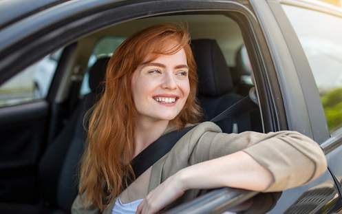 Das Bild zeigt eine junge Frau im Auto, die sich keine Sorgen um die VW-Golf-5-Versicherung für Fahranfänger macht.