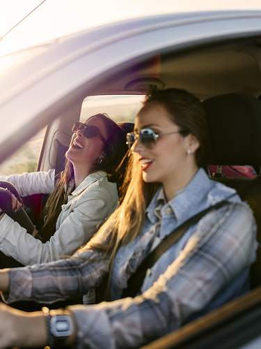 Zwei junge Frauen sitzen lachend in ihrem VW Golf 6.