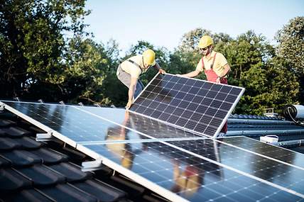 Ein Monteur installiert eine Photovoltaikanlage auf einem Dach.