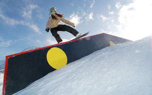 Bei der Abfahrt auf einer Piste springt ein Skifahrer von einem kleinen Felsen.