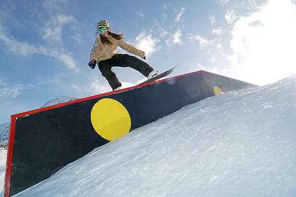 Bei der Abfahrt auf einer Piste springt ein Skifahrer von einem kleinen Felsen.