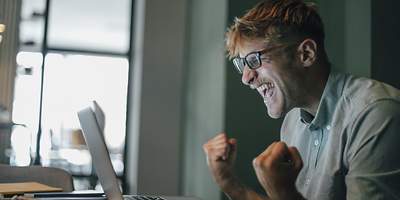 Mann jubelt am Laptop