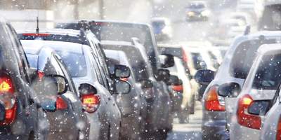 Eine Familie tobt bei Schnee und Eis vor einem Holzhaus. 