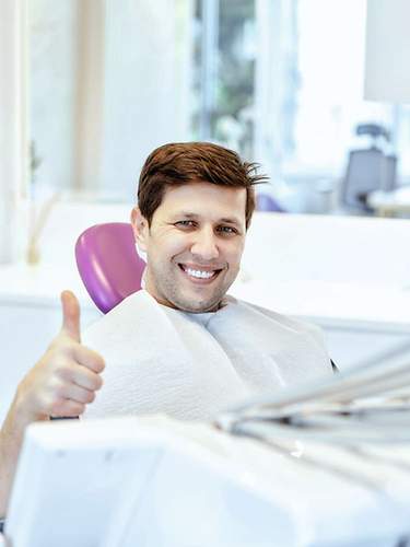 Das Bild zeigt einen Mann beim Zahnarzt, dessen Zahnbrücke von der Versicherung übernommen wird.