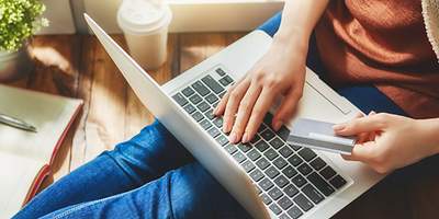 Ein junger Single-Mann tanzt auf seinem Sofa und spielt Luftgitarre.