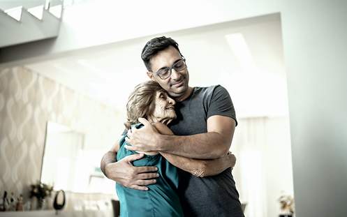 Ein Sohn umarmt seine Mutter. 