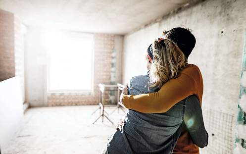Ein Paar umarmt sich in der Baustelle des Hauses und hat dich wichtigsten Versicherung für den Hausbau abgeschlossen. 