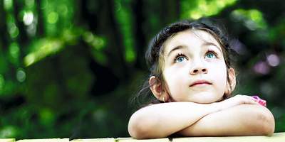 Ein Kind schaut nachdenklich nach oben in den Himmel