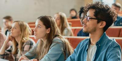 Versicherungen für Studenten. Eine Gruppe von Studenten spaziert über einen Weg.