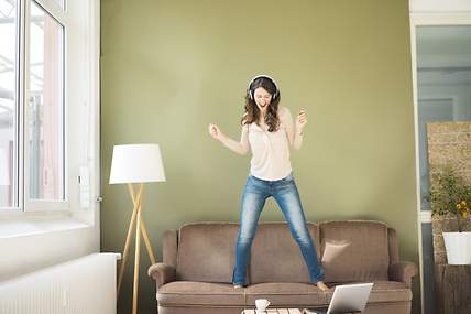 Das Bild zeigt eine junge Frau, die auf einem Sofa tanzt.