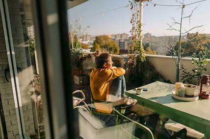 Frau auf Balkon schaut in die Ferne.