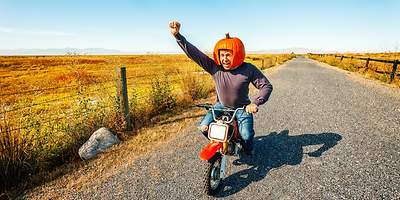 Mann mit Kürbis auf Motorrad.