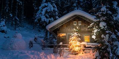 Beleuchtete Blockhütte in winterlicher Landschaft