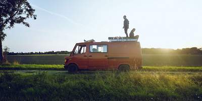 Eine Frau und ein Mann sitzen auf dem Dach eines Wohnmobils.