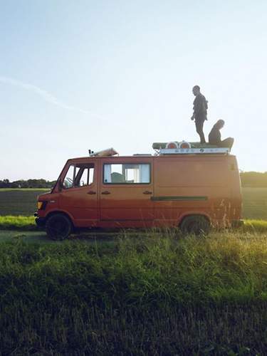 Eine Frau und ein Mann sitzen auf dem Dach eines Wohnmobils.