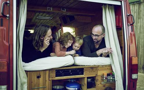 Eine Frau, ein Mann und zwei Kinder liegen in einem Wohnwagen.