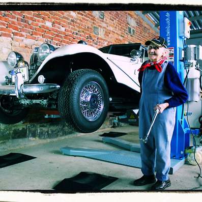 Älterer Mann mit einem Oldtimer in einer Werkstatt