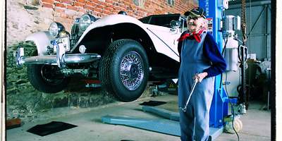 Älterer Mann mit einem Oldtimer in einer Werkstatt