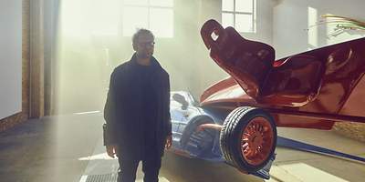 Ein Mann steht vor einer Autoskulptur