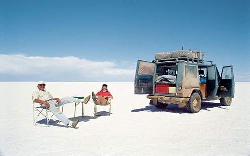 Zwei Personen sitzen neben einem Jeep in der Wüste
