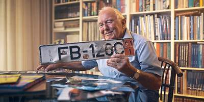 Ein älterer Mann zeigt sein Kennzeichenschild