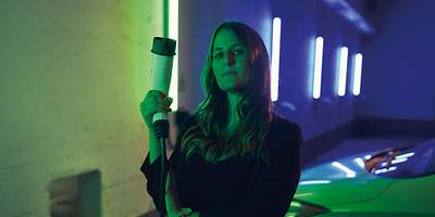 Frau mit Autoladstecker in der Hand