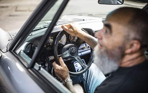 Ein Mannsitzt in einem Auto und lenkt.