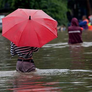 Frau im Wasser mit rotem Regenschirm