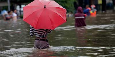 Frau im Wasser mit rotem Regenschirm