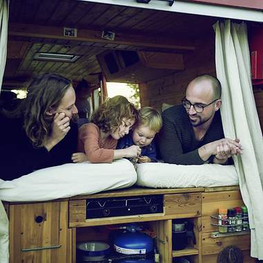Eltern liegen mit ihren zwei Kindern im Bett eines Vans