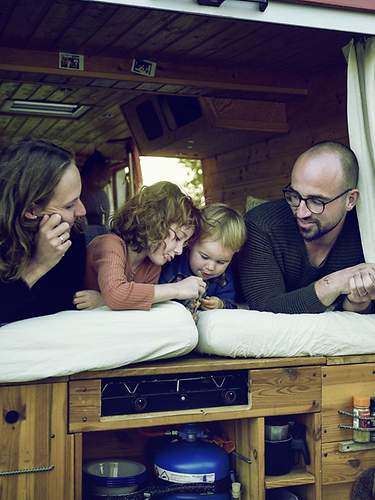 Eltern liegen mit ihren zwei Kindern im Bett eines Vans