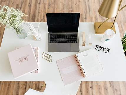 Ein Bürotisch mit einem Planer, Laptop und einem Kaffee
