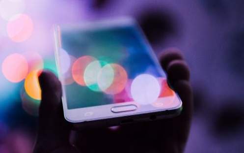 Eine Person hält ein weißes Smartphone in der Hand