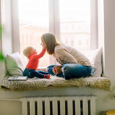 Mutter mit Kind auf einer Fenstersitzbank