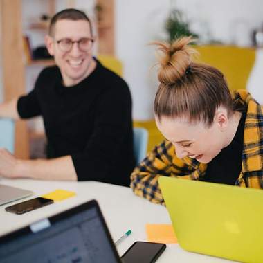 Ein Mann und eine Frau sitzen an einem Tisch vor Laptops.