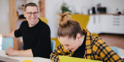 Ein Mann und eine Frau sitzen an einem Tisch vor Laptops.