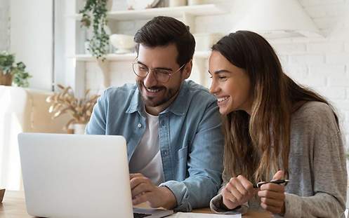 Mann und Frau sitzen lächelnd vor einem Laptop