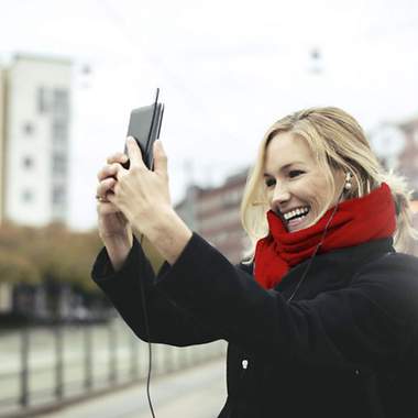 Frau mit rotem Schal und Handy in der Hand