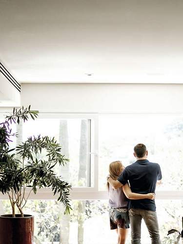 Ein Paar blickt entspannt aus dem Fenster, da sie eine gemeinsame Risikolebensversicherung abgeschlossen haben