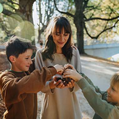 Eine Frau und zwei Kinder sammeln Kastanien