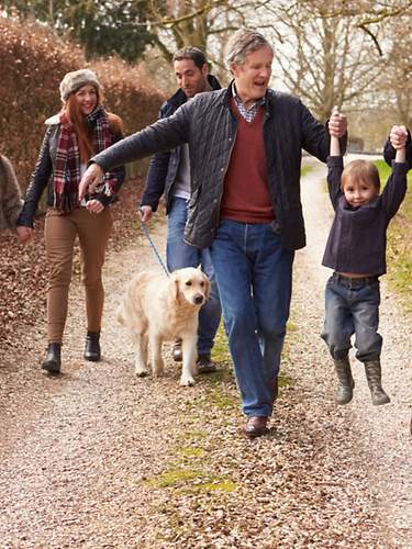 Drei Generationen einer Familie gehen zusammen mit dem Hund im Wald spazieren.