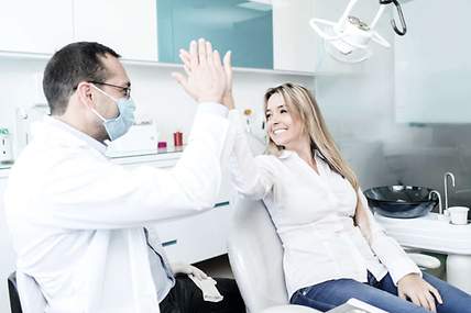 Glückliche Patientin gibt ihrem Zahnarzt nach der Behandlung ein High Five 