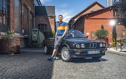 EIn Mann steht vor einem Auto der Marke BMW.