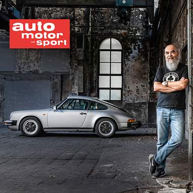 Ein älterer Mann steht vor einem Porsche.
