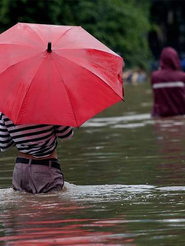 Frau im Wasser mit rotem Regenschirm
